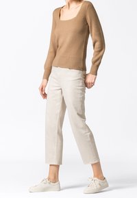 Khakifarbener, gerippter Strickpullover mit quadratischem Ausschnitt, kombiniert mit beigen, verkürzten Hosen und hellen Sneakern. Einfaches und lässiges Ensemble.