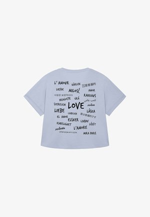 lichtblauw t-shirt met korte mouwen met het woord "LOVE" en vertalingen in verschillende talen, gedrukt in zwart met variërende lettergroottes.