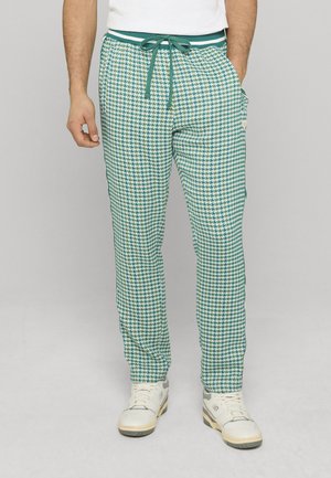 Pantalon de jogging à carreaux verts et blancs avec taille élastique et cordon de serrage, doté de poches latérales et d'une coupe slim.