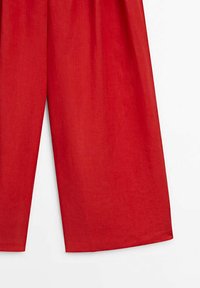 Pantalon en lin rouge, coupe ample, jambes larges et surface texturée. Il présente une taille haute et des ourlets propres et finis.