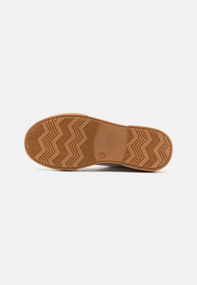 Suela de goma con patrón en zigzag, color marrón claro, textura suave, forma redondeada y un pequeño logo del fabricante en la parte inferior.