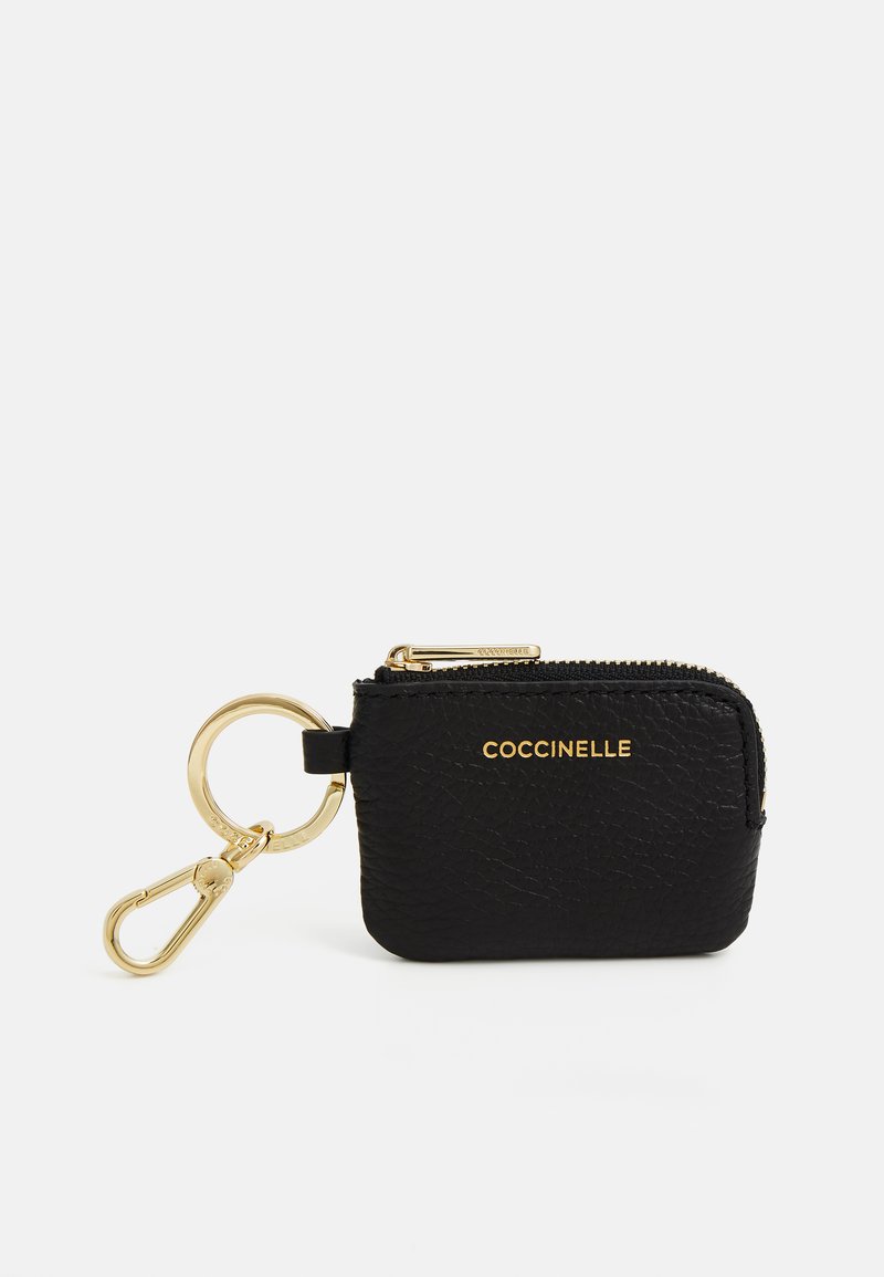 Black leather keychain wallet with a textured finish, gold zipper, and hardware. Features "Coccinelle" embossed in gold on the front.