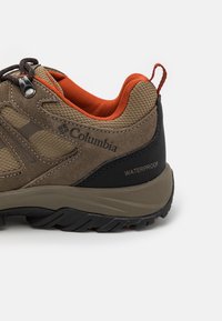 Waterproof hiking shoe featuring a brown suede upper with mesh panels, orange accents, and a black rubber heel cap. Treaded black outsole.