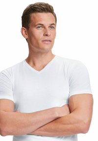 T-shirt blanc à col en V fabriqué en tissu lisse et léger. Manches courtes, design ajusté et subtile brillance dans tout le matériau.