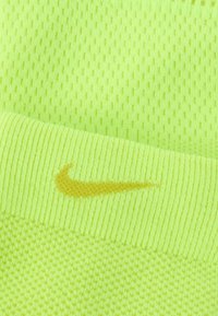 Αθλητικός εξοπλισμός Nike σε έντονο νέον κίτρινο, με υφή από διχτυωτό ύφασμα και ραβδωτές λεπτομέρειες, με μικρή χρυσή λεπτομέρεια λογότυπου Swoosh.