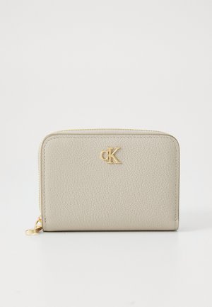 Portafoglio in pelle beige texturizzata con chiusura a zip, caratterizzato da un logo dorato "CK" sul davanti. Forma rettangolare compatta con bordi lisci.