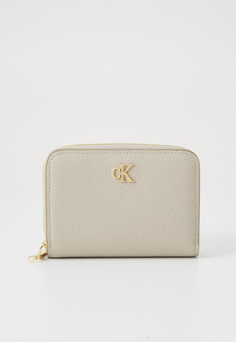 Portafoglio in pelle beige texturizzata con chiusura a zip, caratterizzato da un logo dorato "CK" sul davanti. Forma rettangolare compatta con bordi lisci.