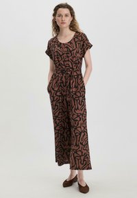 Brauner Jumpsuit mit schwarzem abstraktem Muster, kurzen Ärmeln, tailliertem Bund, weitem Bein und seitlichen Taschen. Weicher Stoff und lockere Passform.