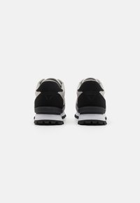 Chaussures de sport noires et grises avec une tige en suède texturé, un col rembourré et une semelle intermédiaire blanche. Présente une semelle extérieure noire robuste pour une meilleure traction.