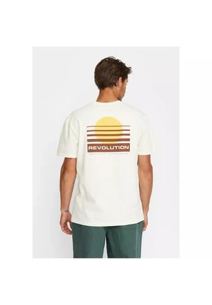 Uomo di spalle che indossa una maglietta bianca con un sole giallo e strisce orizzontali marroni e la scritta "REVOLUTION" sulla schiena.