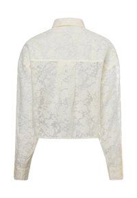Sheer white long-sleeve shirt with a floral pattern, a pointed collar, and buttoned cuffs. Features a yoke at the back and a cropped cut.