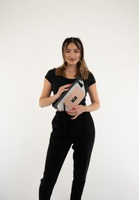 Marsupio in grigio, rosa e nero con tracolla regolabile, tasca con zip e dettaglio del logo; il materiale sembra liscio con un design strutturato.