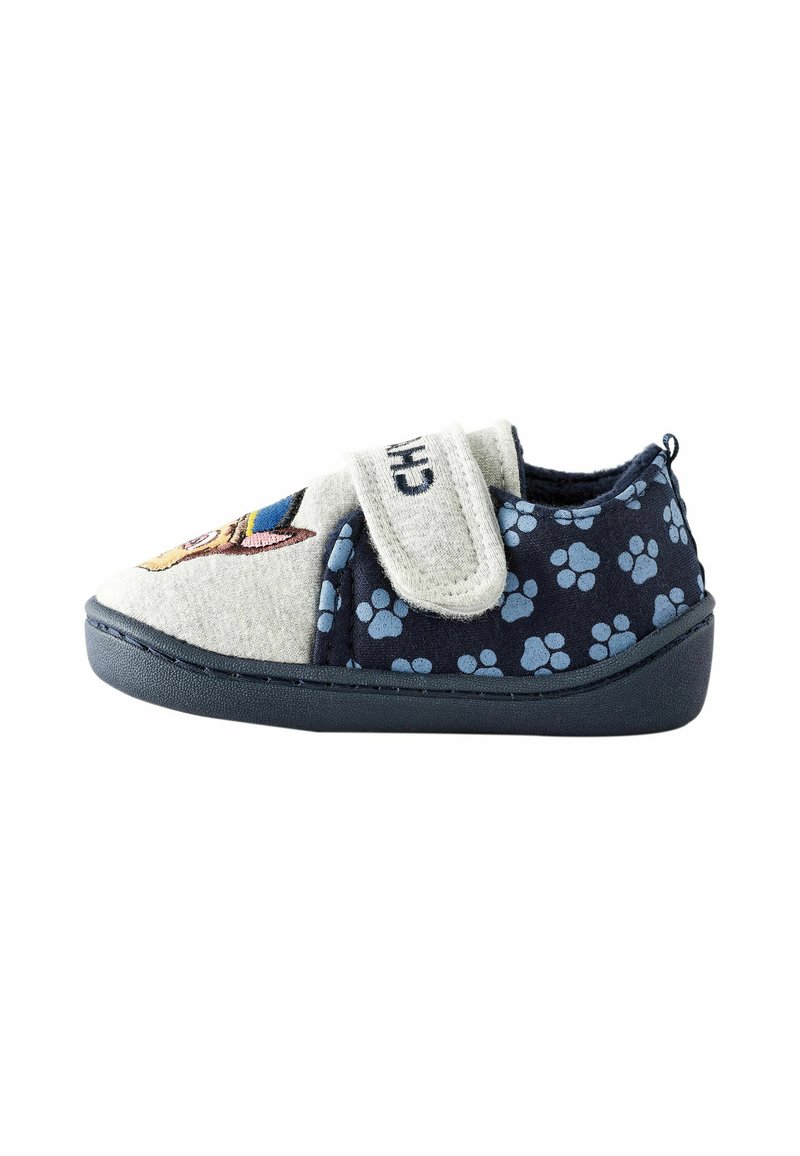 Kinderhausschuhe mit grauem Obermaterial, das ein Hundef design zeigt, navyblauem Boden mit hellblauen Pfotenabdrücken und einem Klettverschluss. Gummisohle.