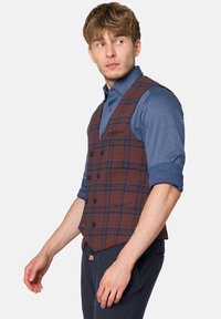 Brązowa kamizelka w kratę wykonana z teksturowanej tkaniny, z dekoltem w kształcie litery V, sześcioma guzikami i dwiema przednimi kieszeniami, noszona na niebieskiej koszuli z długim rękawem.