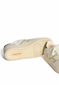 Witte sneaker met beige suède accenten, textuur rubberen zool en logo details. Voorzien van ronde veters en een laag ontwerp.