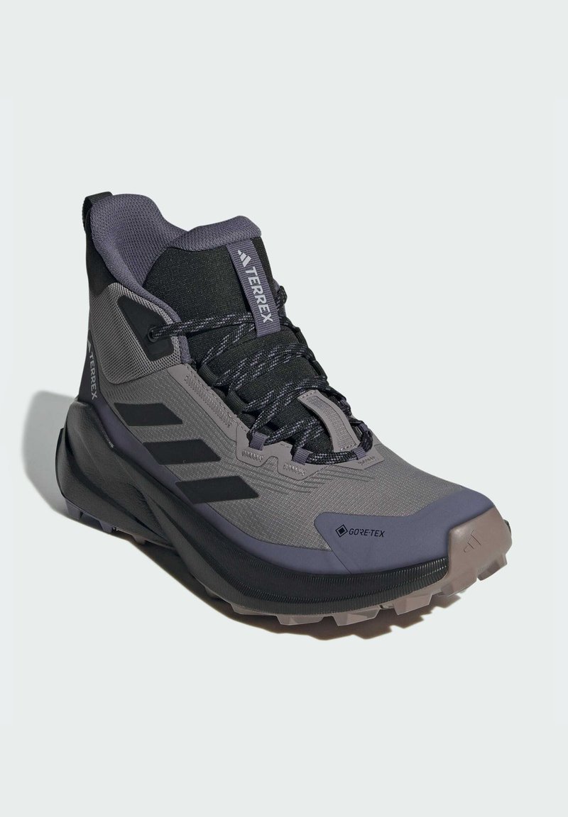 Chaussure de randonnée mi-haute grise et noire en matériau Gore-Tex, avec une tige texturée, un embout renforcé et une semelle extérieure robuste avec des motifs de grip.