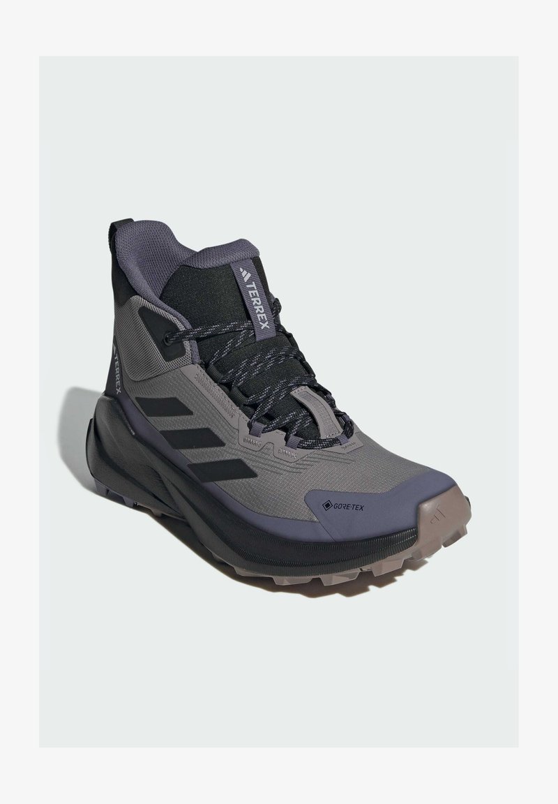 Chaussure de randonnée mi-haute grise et noire en matériau Gore-Tex, avec une tige texturée, un embout renforcé et une semelle extérieure robuste avec des motifs de grip.