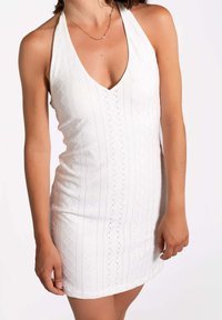 Weißes Halterneck-Kleid mit tiefem V-Ausschnitt, vertikalen bestickten Mustern und figurbetonter Silhouette, ausgestattet mit kurzem Saum und strukturiertem Stoff.