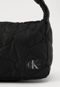 Zwarte gewatteerde tas van nylon met een ronde vorm, een subtiele glans en een Calvin Klein Jeans logo label in zilver.
