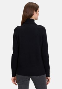 Schwarzer Rollkragenpullover mit geripptem Kragen, strukturiertem Nähten und Knopfakzenten an den Ärmeln, mit lockerer Passform und einfarbiger Gestaltung.