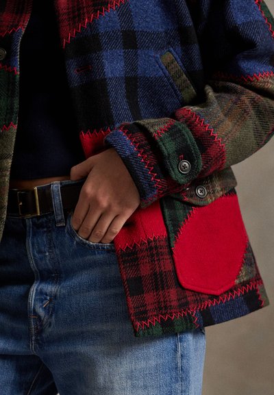 Chaqueta de lana con múltiples patrones que presenta diseños de cuadros en rojo, azul y verde; incluye acentos en rojo contrastante y costuras visibles en los puños.