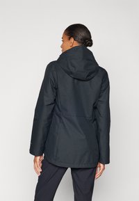 Black waterproof jacket with a hood, featuring a smooth texture, fitted design, and zippered pockets. The back has a subtle seam detail.