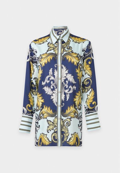 Chemise à manches longues boutonnée avec des motifs floraux baroques complexes en or, blanc et bleu marine sur fond bleu clair.