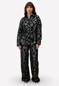 Zwart bloemenprint set bestaande uit een jas met ceintuur en wijd uitlopende broek, gemaakt van een zachte, gestructureerde stof met metalen accenten.