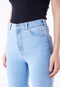 Light blue high-waisted jeans made of denim, featuring five pockets, silver hardware, and subtle stitching details. Smooth texture.