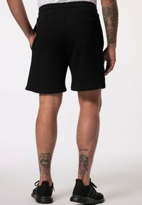 Černé bavlněné šortky s elastickým pasem, které mají zadní kapsu. Materiál je měkký a má ležérní design.