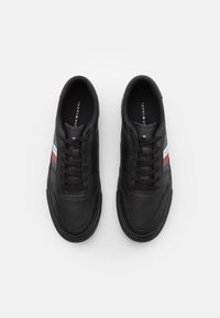 Sneakers in pelle nera con punta rotonda, lacci anteriori e accenti a strisce in rosso, bianco e blu. Superficie testurizzata, suola in gomma.