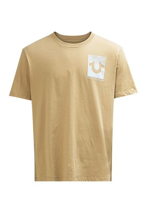 Beige Baumwoll-T-Shirt mit Rundhalsausschnitt. Verfügt über ein weißes Grafiklogo auf der linken Brustseite. Kurze Ärmel und eine entspannte Passform.