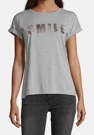 Lichtgrijs T-shirt met opgerolde korte mouwen, met het woord "SMILE" in glanzende metallic letters over de borst. Zachte stof met een losse pasvorm.