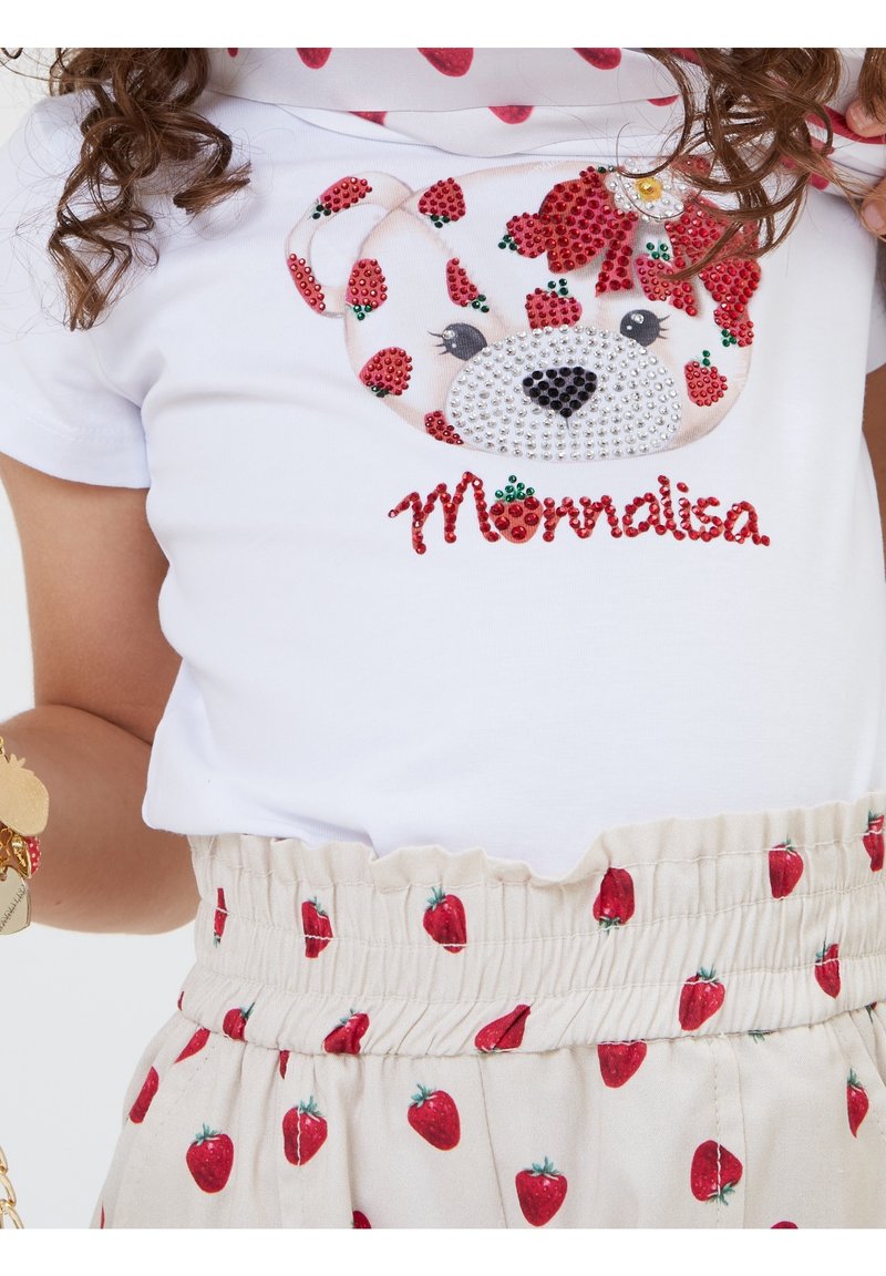 Maglietta bianca in cotone con una faccia di orso realizzata con strass e accenti a forma di fragola. Gonna beige con piccole stampe di fragole rosse.