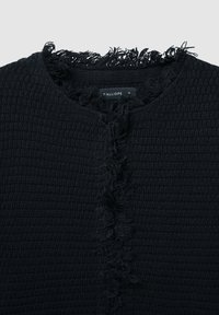 Cardigan nero a maglia con un motivo testurizzato, caratterizzato da bordi sfilacciati lungo il colletto e la parte anteriore, e una semplice chiusura con bottone.