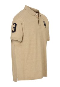 Béžové polokošeľa s golierom, krátkymi rukávmi a tmavomodré číslo „3“ na ľavom rukáve. Na hrudi je logo a bočné rozparky.