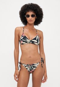 Fekete virágmintás bikini, amely triangel felsővel rendelkezik vékony pántokkal, és állítható kötések oldalakkal ellátott alsóval, nagy levél- és virágmintákkal kiemelve.