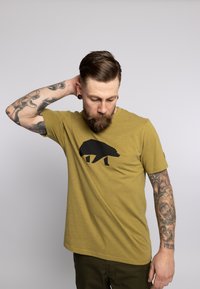 Olijfgroene t-shirt van katoen, met een silhouet van een zwarte beer op de voorkant. Korte mouwen, ronde halslijn en een relaxte pasvorm.