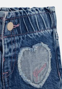 Jeansshorts mit elastischem Bund, ausgestattet mit einem herzförmigen Patch aus hellerem Denim, ausgefransten Kanten und pinken Nähten.