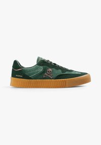 Zapatillas de ante verdes con suela de goma, con un logo bordado de calavera y tibias. Diseño con cordones y acentos texturizados.