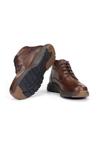 Zapatos de cuero marrón con punta redondeada, diseño de cordones y superficie texturizada. Presentan una suela de goma con patrones de tracción y un tacón en contraste.