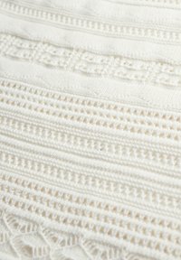 Weißes gewobenes Textil mit komplexen Mustern und verschiedenen Texturen, einschließlich Durchbrüchen und festen Abschnitten, die einen geschichteten visuellen Effekt erzeugen.