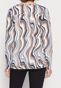 Blusa a maniche lunghe con un motivo a onde multicolore in marrone, blu e bianco. Realizzata in tessuto leggero con una vestibilità comoda.