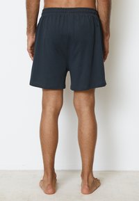 Mörkgrå bomullsshorts med elastisk midjeresår, som har en avslappnad passform och en mjuk yta, som når till mitten av låret.