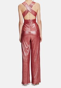 Röd metallisk jumpsuit med korsryggsremmar, figurnära midja och vida byxor med en glänsande, texturerad yta.