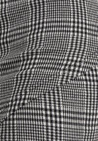 Tissu en damier noir et blanc avec une texture tissée, affichant un design géométrique et une finition douce.