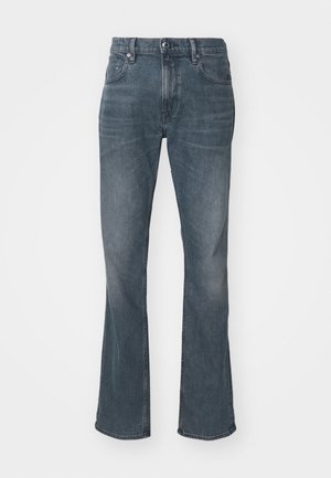 Jean en denim évasé de couleur bleu moyen avec une finition délavée, comprenant une fermeture à bouton et à glissière, un design à cinq poches et des détails de couture.