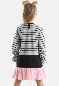 Randig grå topp med långa ärmar, svart bodice och rosa volangkant. Nyckelhålsdetalj på baksidan. Mjuk bomullsmaterial genom hela plagget.