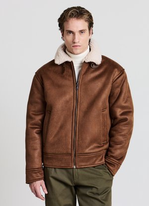 Giacca marrone in ecopelle con colletto in shearling crema, chiusura frontale con cerniera e due tasche laterali. Texture liscia, vestibilità strutturata.