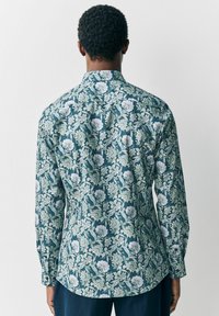 Langarmhemd aus dunkeltürkisfarbenem Baumwollstoff mit einem floralen Muster, das weiße und grüne Blumen zeigt, klassischem Kragen und geknöpften Manschetten.